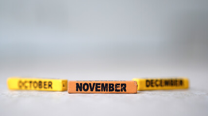 Wooden block calendar with focus on NOVEMBER, October December blur. silver background