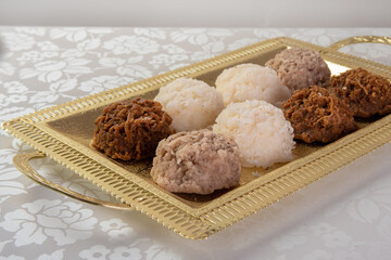 Brazilian cocada (coconut candy) placed on a golden tray on a table with white towel, selective focus.