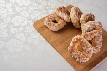sugar-coated sweet cookies placed on a polished board on a table with white tablecloth, selective focus.