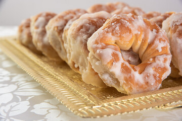 sugar-coated sweet cookies placed on a golden tray on a table with white tablecloth, selective focus.