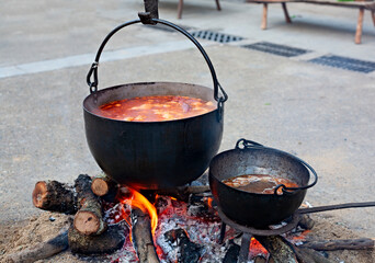 Making the food in two old cast iron pots on a wood fire and in which a delicious stew is being...