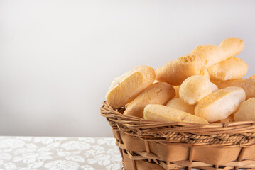 Traditional Brazilian starch biscuit called biscoito de polvilho in a basket on a table covered with white tablecloth, selective focus.