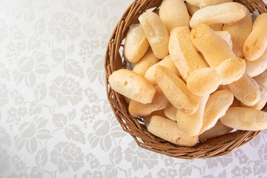 Traditional Brazilian starch biscuit called biscoito de polvilho in a basket on a table covered with white tablecloth, Top view