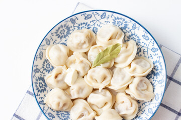 Dumplings in a blue plate on a checkered towel. Ravioli with meat
