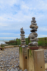 Stacked towers of stones on the beach with old wooden groyne in the background