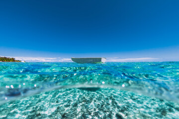 Fototapeta na wymiar Turquoise ocean with sandy bottom in tropics and fishing boat