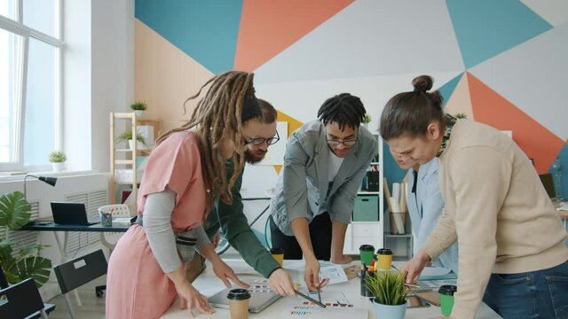 Zoom-in slow motion of creative youth multiracial team of developers discussing smartphone application colors in office. People and job concept.