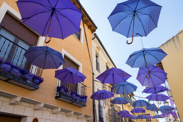 Fototapeta na wymiar violet umbrellas are open to protect streets from the sun light in brihuega town, spain