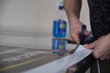 Man cutting print paper with scissors