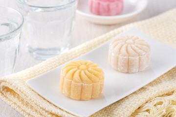 Colorful snow skin moon cake, sweet snowy mooncake, traditional savory dessert for Mid-Autumn Festival on bright wooden background, close up, lifestyle.