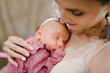 Portrait of young mother keep in arms, hugging child kid baby girl, celebrating birthday holiday party. Happy family: mother and newborn daughter.