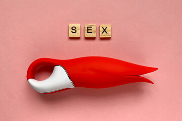 Adult toy. Red vibrator on a pink background
