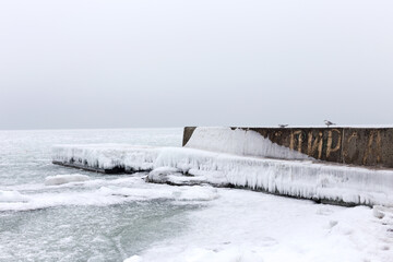Sea covered with broken ice. Front focus. Black sea in winter. Inscription of yellow paint on wall of pier in Russian is the pier.