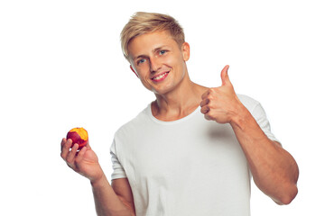 A handsome young guy in a white T-shirt with a peach in his hand