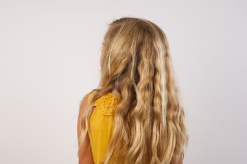 The back side view of a beautiful Little girl with beautiful blonde hair over white background. Studio Shoot.