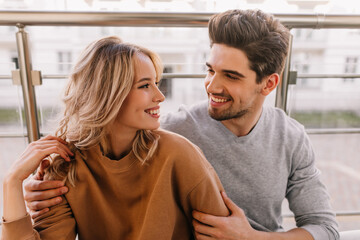 Glad guy embracing girlfriend. Portrait of caucasian couple smiling to each other.