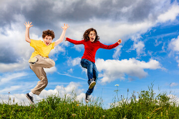 Fototapeta na wymiar Girl and boy running, jumping against blue sky 