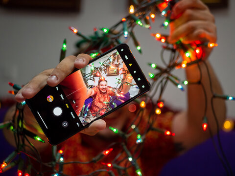 Hombre con orejas de elfo haciendose una foto selfie con las luces de navidad