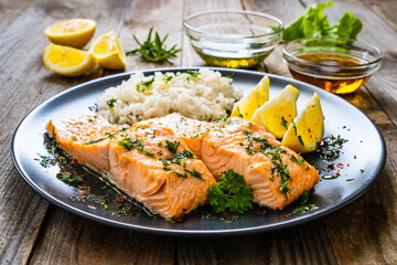 Roasted salmon steaks with lemon, basmati rice and lemon served on wooden table

