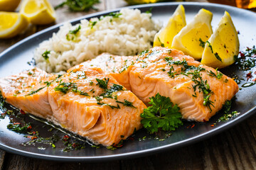 Roasted salmon steaks with lemon, basmati rice and lemon served on wooden table
