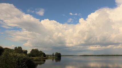 Fototapeta na wymiar Huge white beautiful clouds over lake in summer, Russia