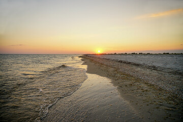 sunset with orange sun on the seashore. The wave runs ashore