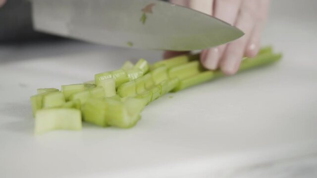 Curring vegetables on a white cutting board to cook vegetarian white bean soup.