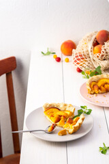 Delicious piece of pie from shortcrust pastry with peach on a plate with a fork, baked in the oven peach clafoutis