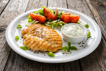 Fried chicken breast with vegetable salad and cream sauce  on wooden table
