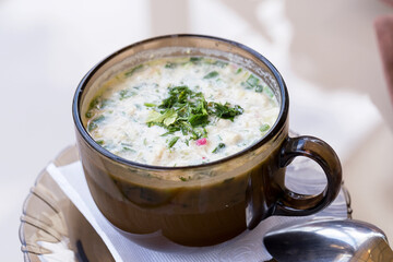 Summer yoghurt cold soup with radish, cucumber, and dill on woodwn table. Okroshka Russian traditional dish