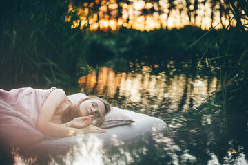 Woman sleeping on a mattress against the lake.