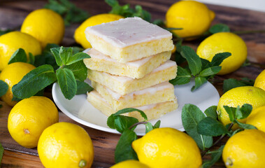 Sliced shortcake, many lemons and mint on wooden table