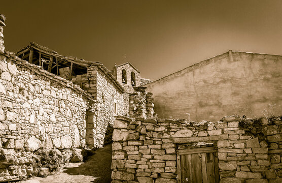 monochrome of old houses made of stone and the church in Rello village, province of Soria, Castile and Leon, Spain