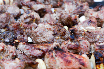 Grilled kebab cooking on metal skewer. Roasted meat cooked at barbecue. BBQ fresh beef meat chop slices. Traditional eastern dish, shish kebab. Grill on charcoal and flame, picnic, street food
