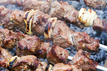 Grilled kebab cooking on metal skewer. Roasted meat cooked at barbecue. BBQ fresh beef meat chop slices. Traditional eastern dish, shish kebab. Grill on charcoal and flame, picnic, street food