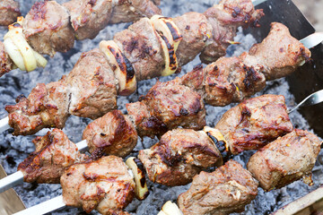 Grilled kebab cooking on metal skewer. Roasted meat cooked at barbecue. BBQ fresh beef meat chop slices. Traditional eastern dish, shish kebab. Grill on charcoal and flame, picnic, street food