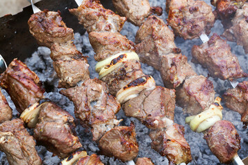 Grilled kebab cooking on metal skewer. Roasted meat cooked at barbecue. BBQ fresh beef meat chop slices. Traditional eastern dish, shish kebab. Grill on charcoal and flame, picnic, street food