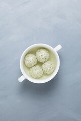 Chicken or turkey meatballs with spinach in bone broth. Gray background, top view. A healthy dietary product with collagen, which provides the body with amino acids