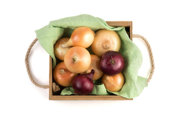 Onions of different varieties in a beautiful wooden packing box on a linen napkin, isolated on a white background, top view. Vegetable background. Concept of natural products.