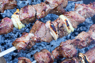 .Grilled kebab cooking on metal skewer. Roasted meat cooked at barbecue. BBQ fresh beef meat chop slices. Traditional eastern dish, shish kebab. Grill on charcoal and flame, picnic, street food
