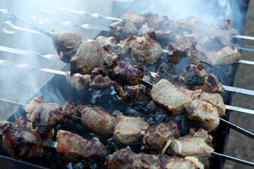 Grilled kebab cooking on metal skewer. Roasted meat cooked at barbecue. BBQ fresh beef meat chop slices. Traditional eastern dish, shish kebab. Grill on charcoal and flame, picnic, street food