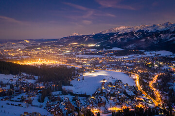Blue and orange Zakopane in winter at night, aerial view
