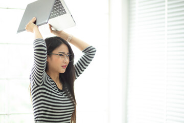 Stressed woman screaming and destroying her laptop. Businesswoman stressed from work breaks her laptop.