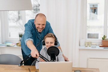 Excited father helping his son record a podcast