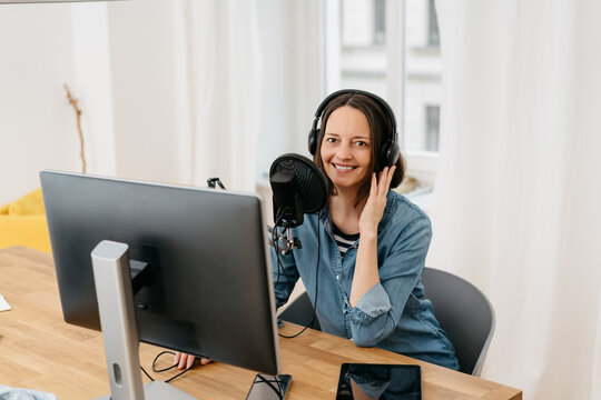 Smiling woman recording a podcast in her office