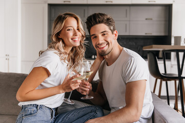 Lovable woman drinking champagne with happy smile. Excited young people celebrating anniversary.