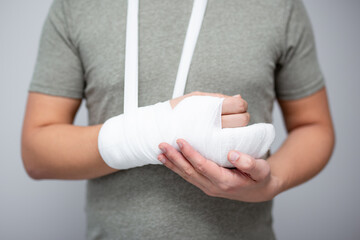 first aid concept - close up of male hand with bandage and gypsum