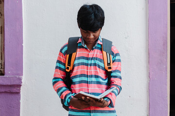 Portrait of an Indian kid wearing backpack reading book