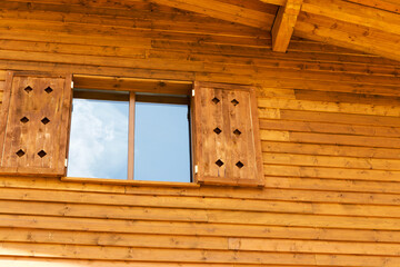 Wooden cabin in the forest under construction. Raw materials. Reflection of sky in windows.