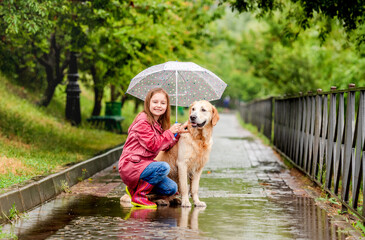 Little girl sharing umbrella with dog